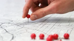 Hand placing a pushpin on a map
